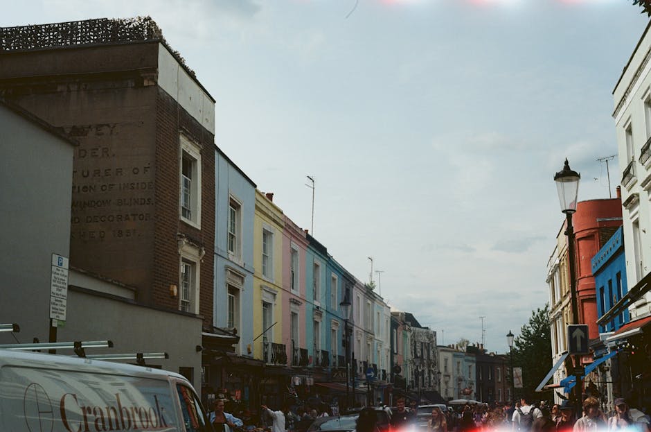 A two-storey brick building with a dark green facade and white window frames, labeled 'Notting Hill Garage' with signage indicating it offers car servicing and repairs, situated on a residential stree